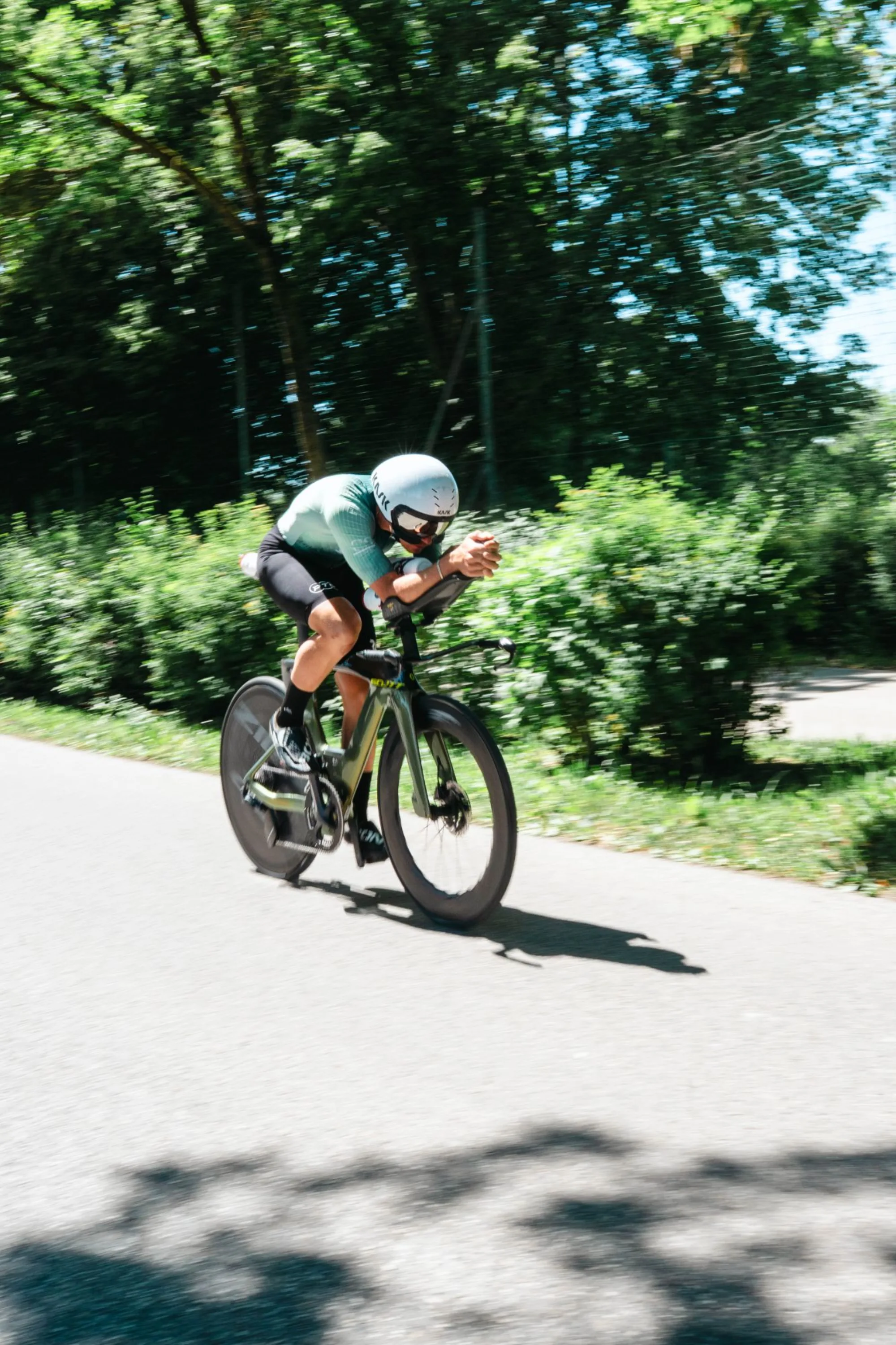 Athlete in a mint custom kit on the time trial bike